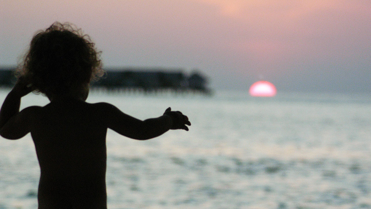 A child watches the sunset in the Maldives (Pixabay)